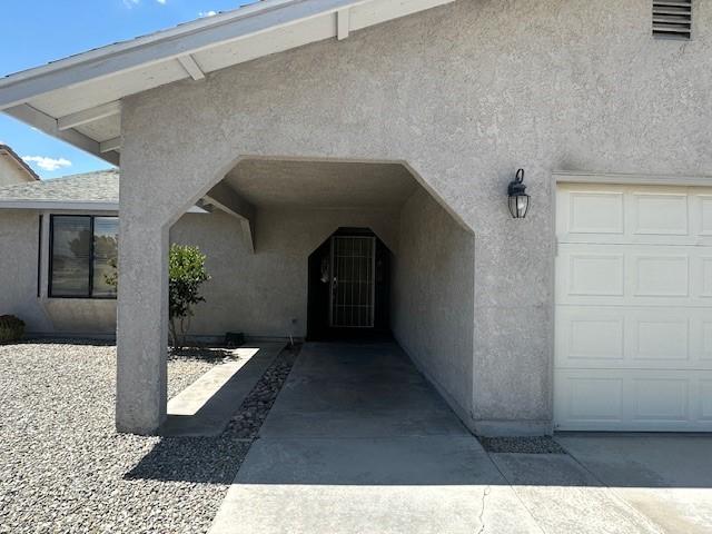 view of exterior entry featuring a garage and stucco siding