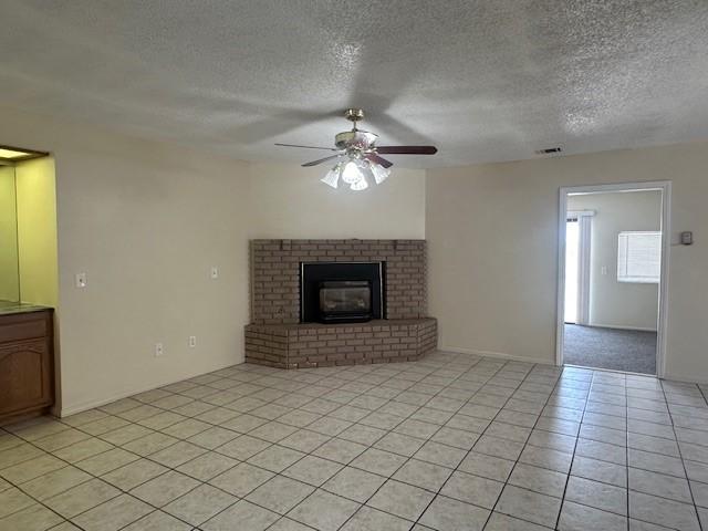 unfurnished living room featuring a textured ceiling, a ceiling fan, light tile patterned flooring, and visible vents
