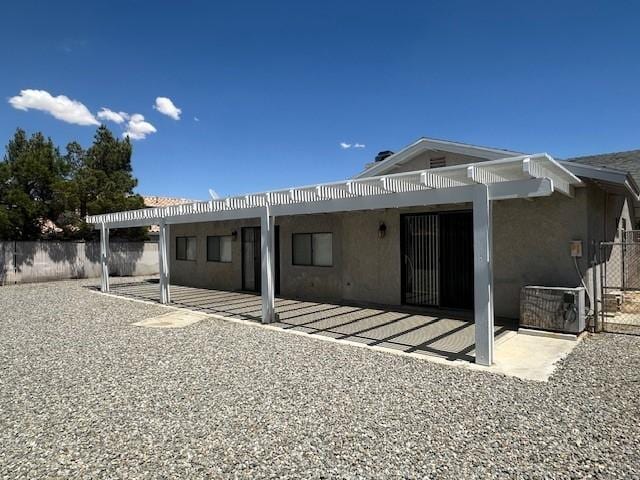 rear view of property featuring fence, a patio, stucco siding, and central AC unit