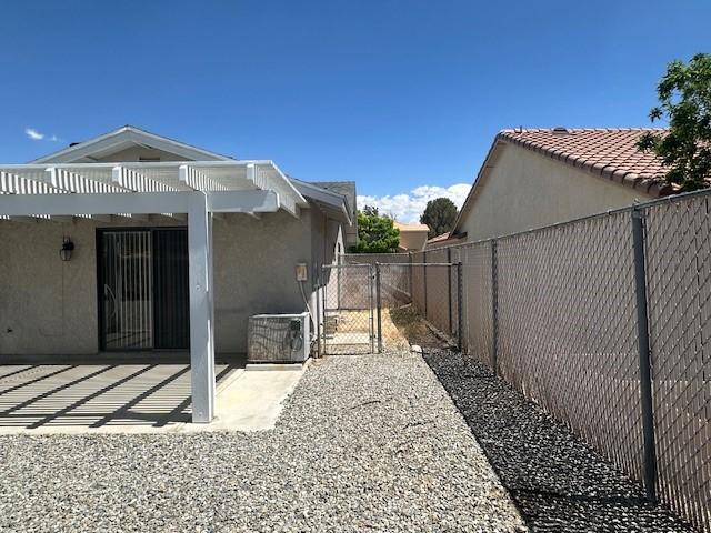 view of property exterior with fence, stucco siding, central AC unit, a gate, and a patio area