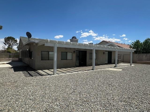 back of property with a chimney, a patio area, fence, a pergola, and stucco siding