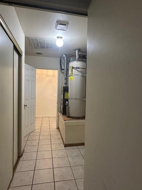 hallway with water heater, light tile patterned floors, and visible vents