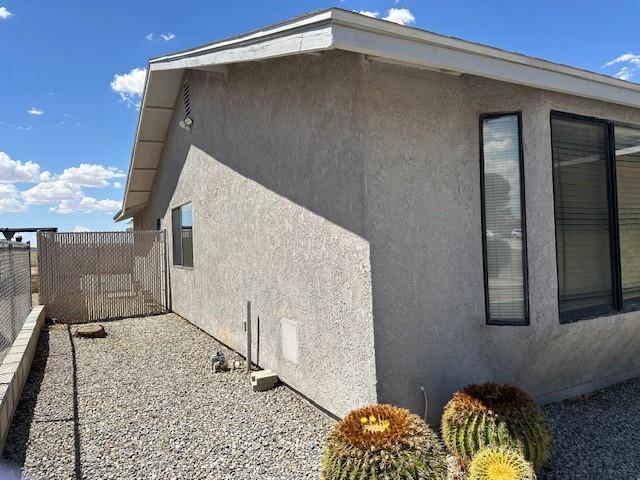 view of side of home with fence and stucco siding