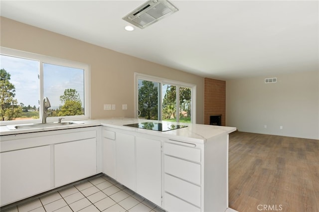 kitchen with visible vents, a sink, black electric cooktop, and a peninsula