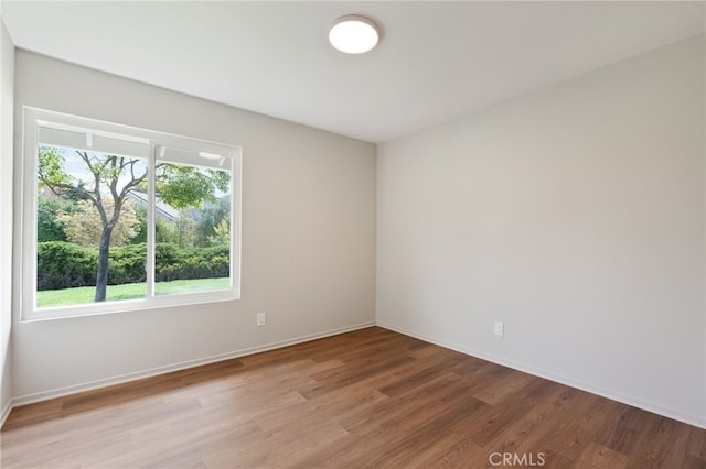 empty room with baseboards, light wood finished floors, and a wealth of natural light