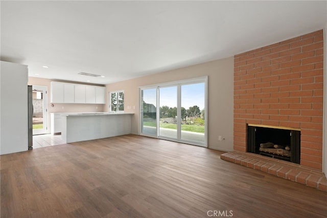 unfurnished living room featuring a brick fireplace and light wood-style floors