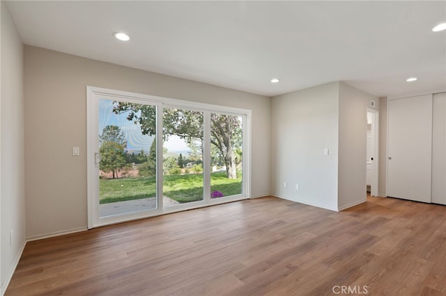 empty room with recessed lighting, light wood-style flooring, and baseboards