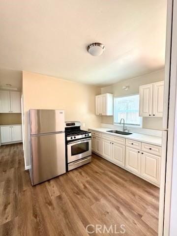5214 Golden Ave, Riverside, CA 92505 - kitchen featuring appliances with stainless steel finishes, wood finished floors, a sink, light countertops, and white cabinetry