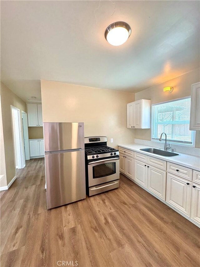 5214 Golden Ave, Riverside, CA 92505 - kitchen with appliances with stainless steel finishes, a sink, light countertops, light wood-style flooring, and white cabinetry