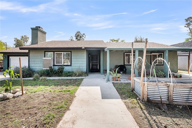 ranch-style home featuring an attached garage, a chimney, and a shingled roof
