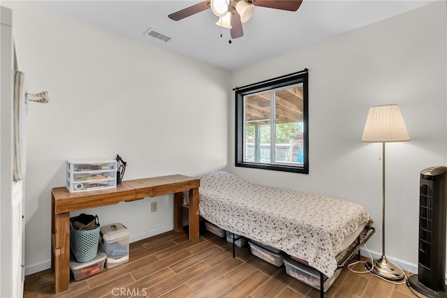 bedroom with visible vents, a ceiling fan, baseboards, and wood finished floors