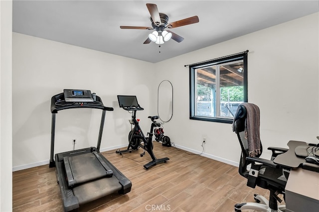 exercise room with a ceiling fan, baseboards, and light wood finished floors