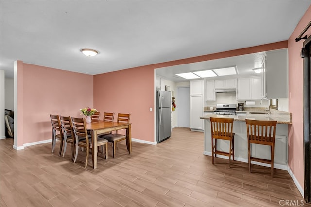 dining room with light wood-type flooring and baseboards