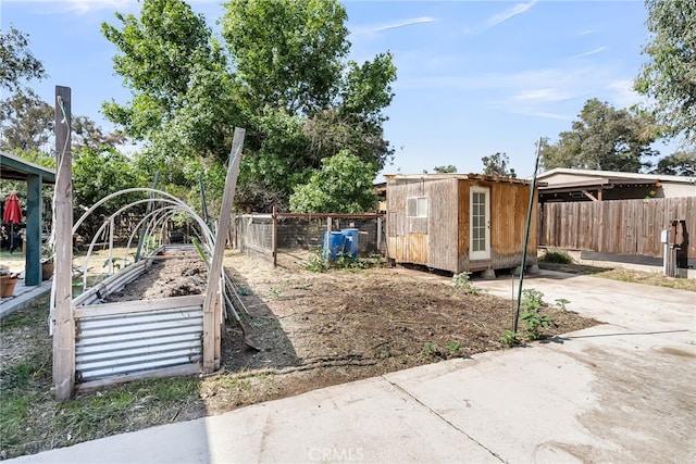 view of yard with a fenced backyard, an outdoor structure, a vegetable garden, and a storage shed