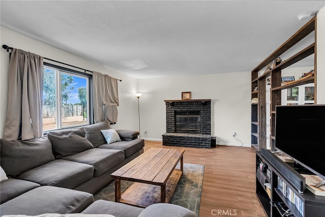 living room with baseboards, a brick fireplace, and wood finished floors