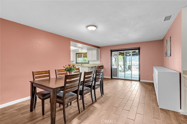 dining room with baseboards, visible vents, and light wood finished floors