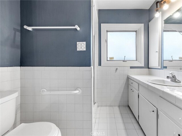 449 Highland Ave, Barstow, CA 92311 - bathroom with tile walls, plenty of natural light, tile patterned floors, and toilet