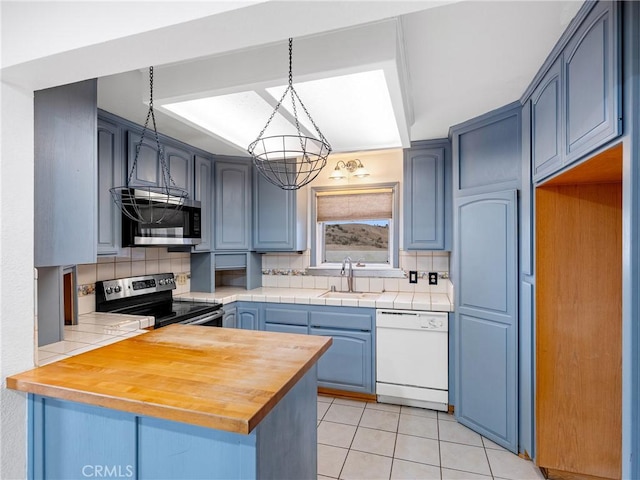 449 Highland Ave, Barstow, CA 92311 - kitchen with light tile patterned flooring, appliances with stainless steel finishes, a sink, a peninsula, and decorative backsplash
