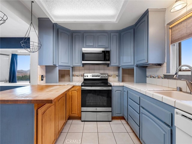 449 Highland Ave, Barstow, CA 92311 - kitchen featuring decorative backsplash, a peninsula, light tile patterned flooring, a sink, and stainless steel appliances