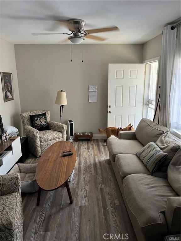 living area featuring a ceiling fan, baseboards, and wood finished floors
