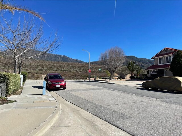 6483 N Walnut Ave, San Bernardino, CA 92407 - view of asphalt road featuring a mountain view, curbs, street lights, and sidewalks