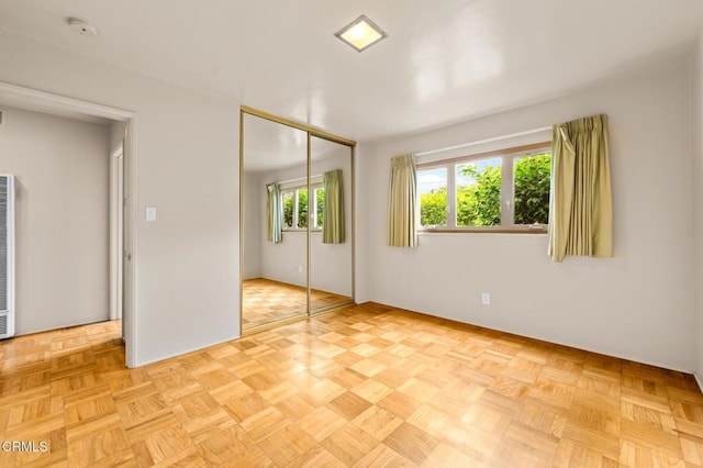 unfurnished bedroom featuring a closet, a heating unit, and baseboards