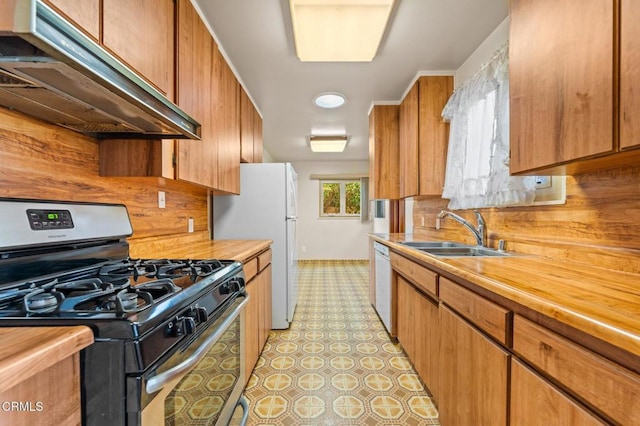 kitchen with butcher block counters, gas range, under cabinet range hood, a sink, and dishwasher