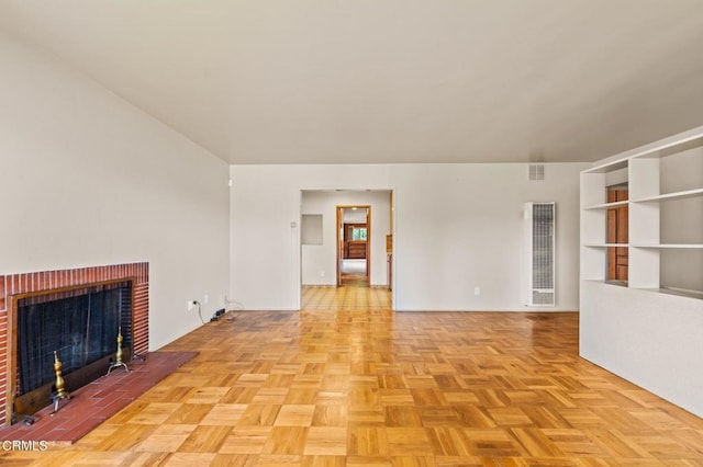 unfurnished living room with a heating unit and a brick fireplace
