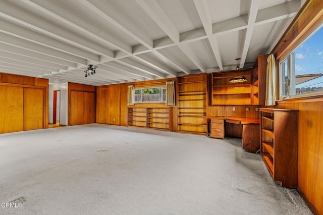 interior space featuring wood walls, built in desk, light carpet, and beamed ceiling