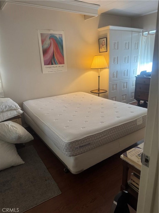 bedroom featuring ornamental molding and wood finished floors