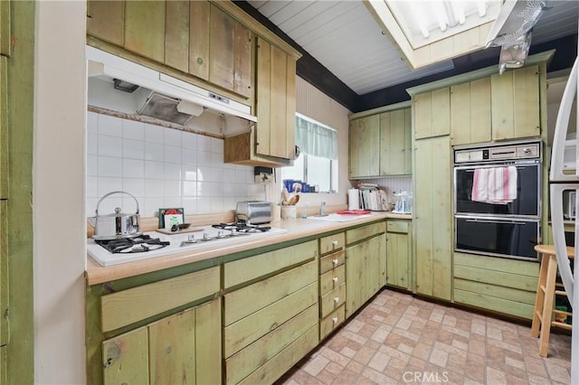 2218 Pacific Ave, Venice, CA 90291 - kitchen with under cabinet range hood, tasteful backsplash, light countertops, white stovetop, and brick patterned flooring
