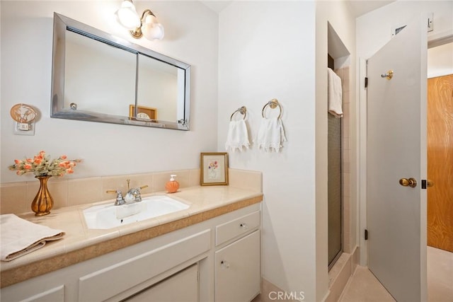 bathroom featuring a shower with shower door and vanity