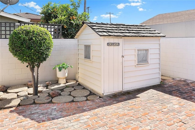 view of outbuilding featuring fence and an outbuilding