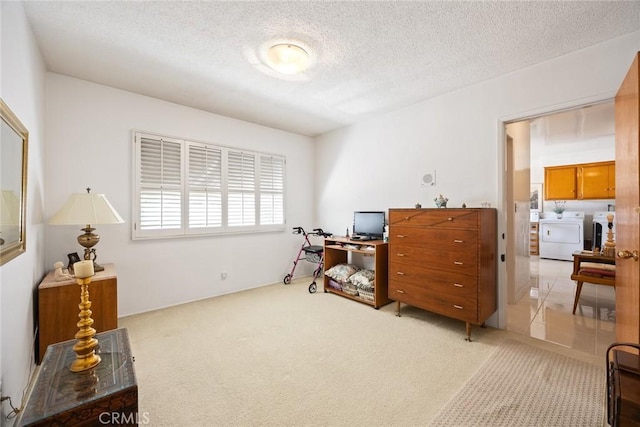 office featuring a textured ceiling, light colored carpet, and washer and clothes dryer