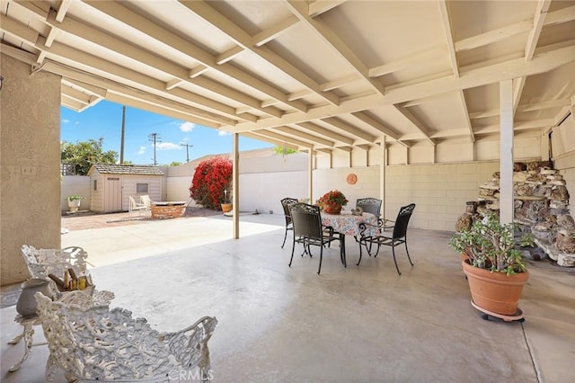 view of patio featuring a fenced backyard, a shed, an outbuilding, and outdoor dining space
