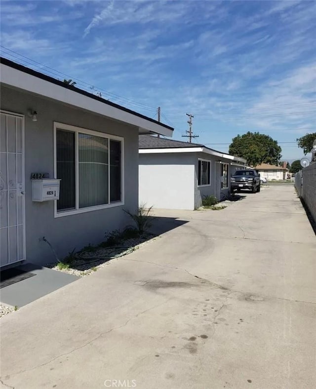 view of side of home with stucco siding and fence