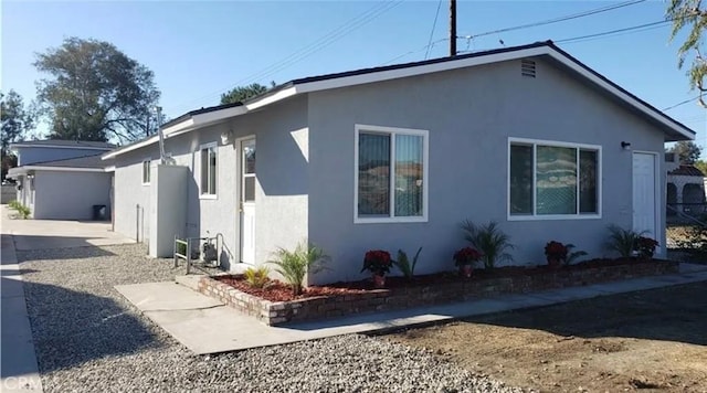 view of home's exterior with stucco siding and fence