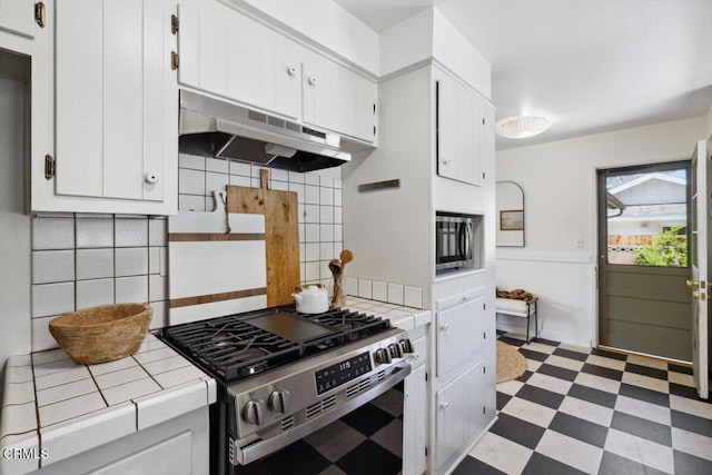921 Topaz Ct, Ojai, CA 93023 - kitchen featuring light floors, tile counters, under cabinet range hood, a wainscoted wall, and appliances with stainless steel finishes