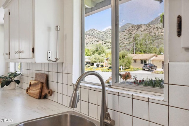 921 Topaz Ct, Ojai, CA 93023 - interior details featuring a sink, backsplash, a mountain view, and white cabinetry