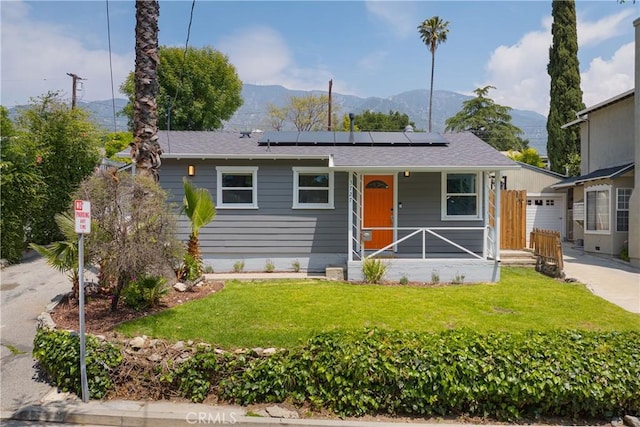 view of front of home featuring a porch, a front lawn, roof mounted solar panels, and a mountain view