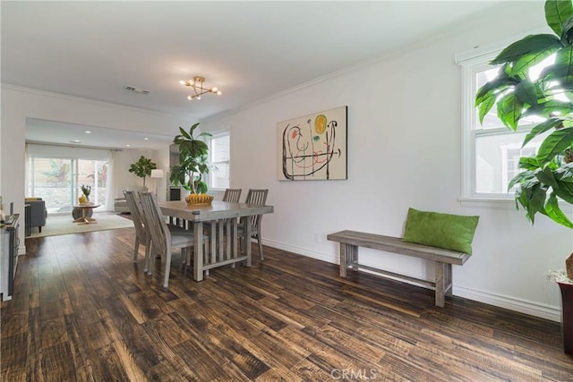 dining area featuring dark wood-type flooring, ornamental molding, and baseboards