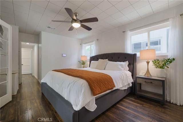 bedroom with ceiling fan, dark wood-style floors, and visible vents