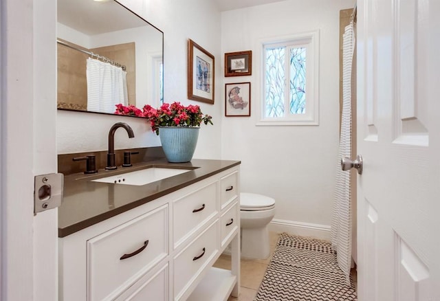 bathroom with vanity, tile patterned flooring, baseboards, and toilet