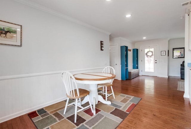 dining space with crown molding, a wainscoted wall, wood finished floors, and visible vents