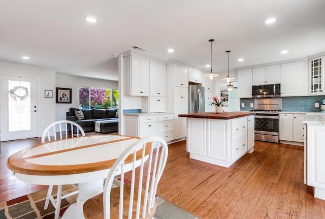 kitchen with visible vents, a center island, wood-type flooring, stainless steel appliances, and butcher block countertops