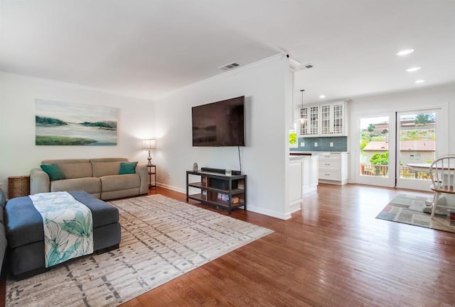 living area with recessed lighting, visible vents, and wood finished floors