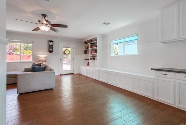 living room with a ceiling fan, dark wood-style flooring, built in shelves, and visible vents