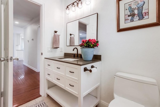 half bathroom with vanity, baseboards, toilet, and wood finished floors