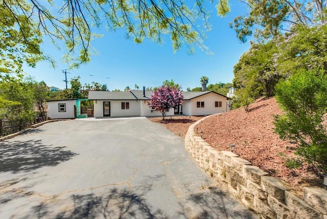 ranch-style home featuring stucco siding, fence, and driveway