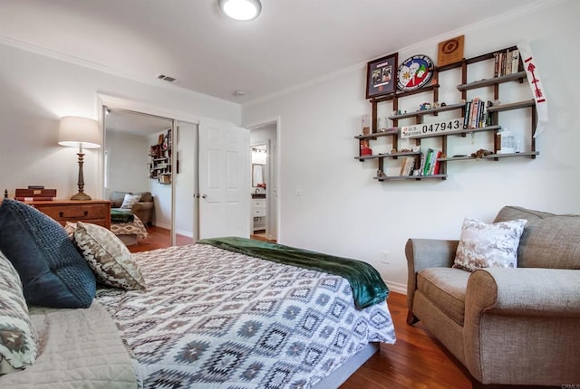 bedroom with baseboards, ornamental molding, wood finished floors, and visible vents